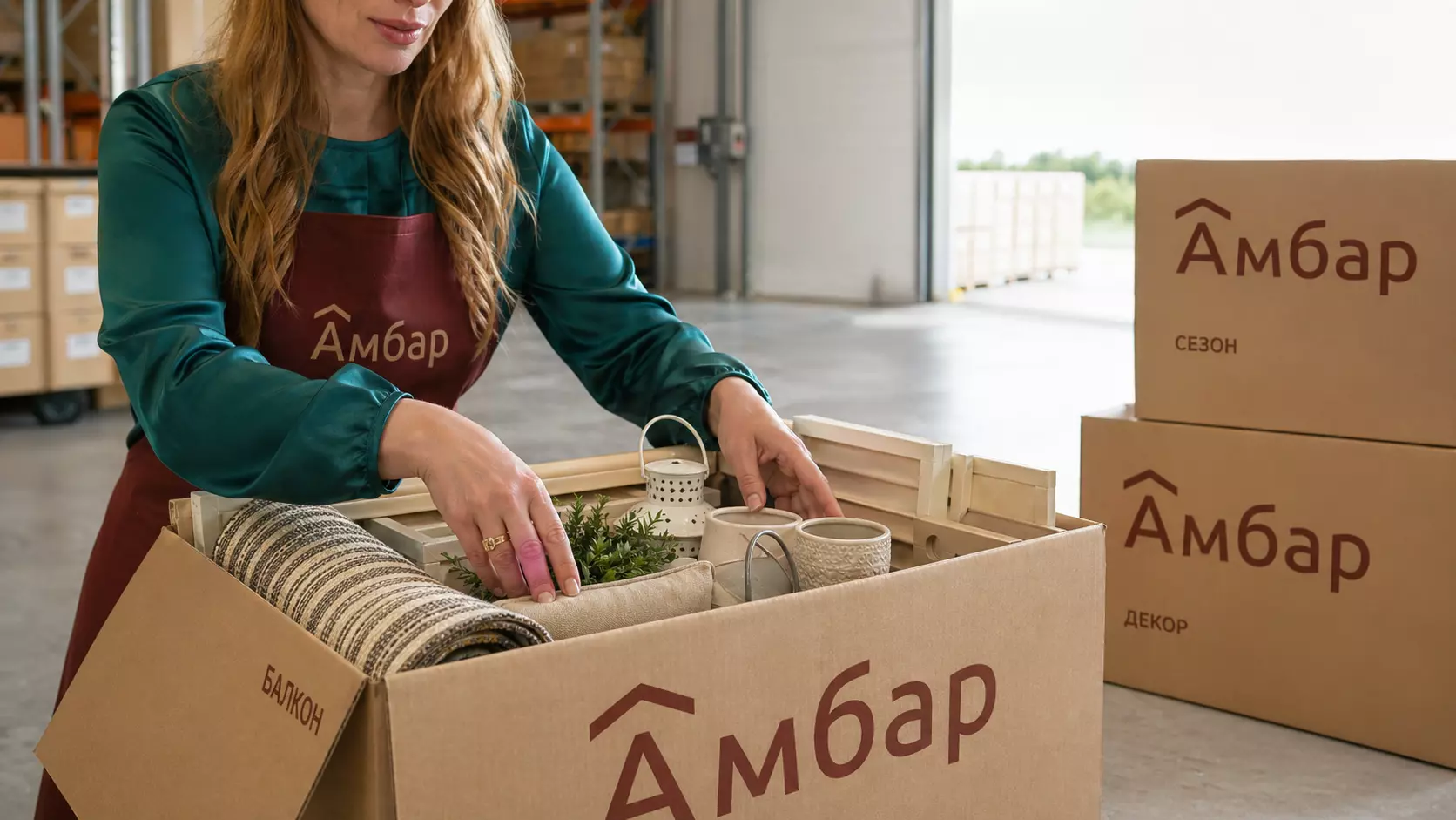 Сотрудник аккуратно упаковывает вещи с балкона в коробку АМБАР на складе